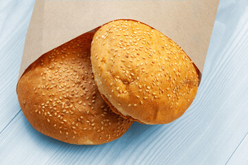 burger buns in a package on a wooden background. appetizing buns with sesame in a paper package	