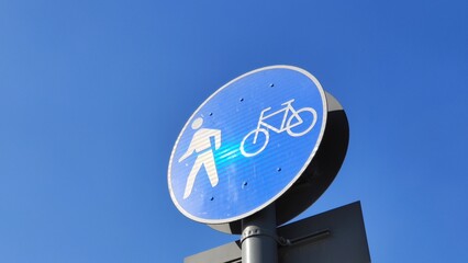 Be aware of pedestrians crossing and bike lines ahead with blue and white round traffic signs on a...