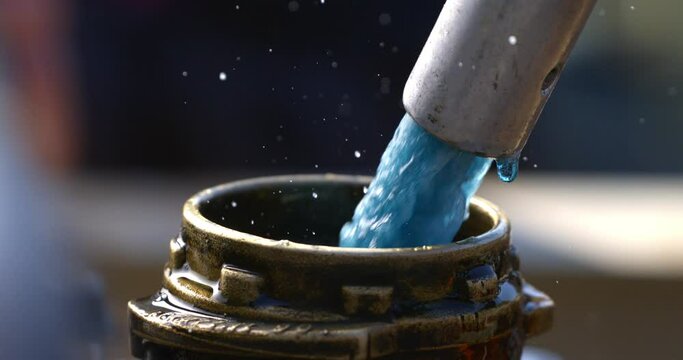Super slow motion close up of liquid diesel fuel is flowing from tank to fill can at plant industrial factory at 1000 fps.