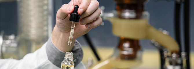 Close up of a researcher holding hemp oil in a laboratory. Herbal alternative for medicine. A...