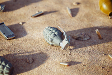 Close-up view of a grenade on the sandy ground surrounded by combat equipment