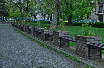 A long wooden bench in an authentic flower garden with nature reviving in spring, Sofia, Bulgaria