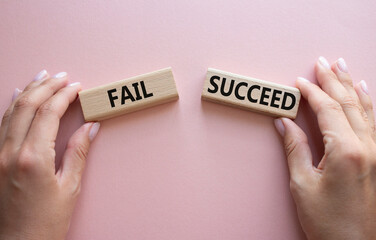 Fail or Succeed symbol. Concept word Fail or Succeed on wooden blocks. Businessman hand. Beautiful pink background. Business and Fail or Succeed concept. Copy space