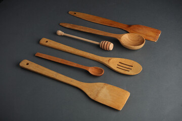 Set of different wooden spoons and spatula on dark gray background