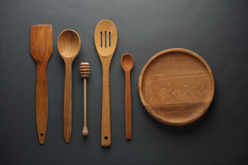 Wooden kitchen utensils on dark gray background. Top view