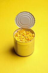 Canned corn in a tin can on yellow background