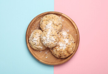 Homemade cereal cookies on a wooden plate. Blue pink background