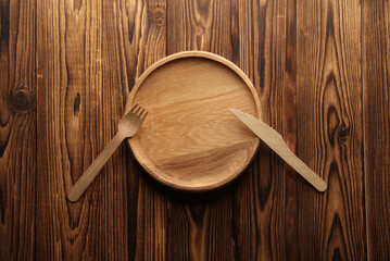 Wooden plate with knife and fork on boards. Eco concept
