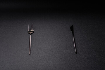 Cutlery fork, knife and spoon on a dark textured concrete background