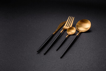 Cutlery fork, knife and spoon on a dark textured concrete background