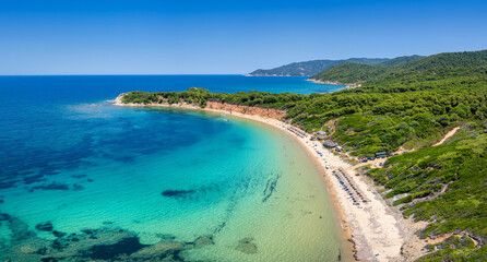 Aerial view of Mantraki beach with emerald sea and lush pine tree forrest at the island of Skiathos, Sporades, Greece