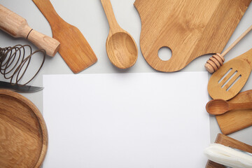 Kitchen utensils with a white sheet of paper on a gray background. Copy space