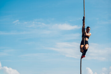 Female partake in an obstacle course race while preparing to climb the rope