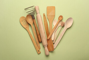 Set of wooden eco kitchen utensils on green background. Flat lay. Top view