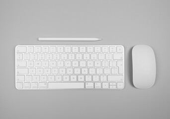Top view of white keyboard, mouse and pen on light grey background. Modern office flat lay, copy space.