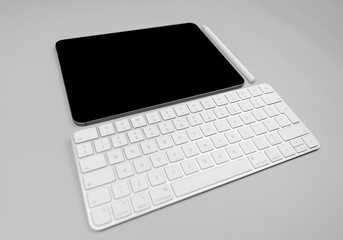 White keyboard, tablet and pen on light grey background. Modern office, copy space.