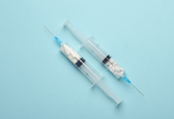 Syringes with pills inside on blue background. Medicine concept