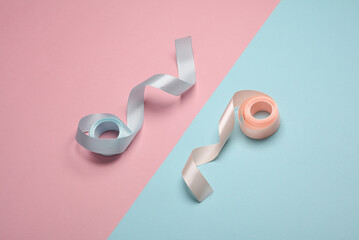 Rolls of santin ribbons on a blue-pink pastel background