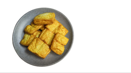 Fried tofu on a plate isolated on white background, yellow tofu or takwa tofu on a dining plate.