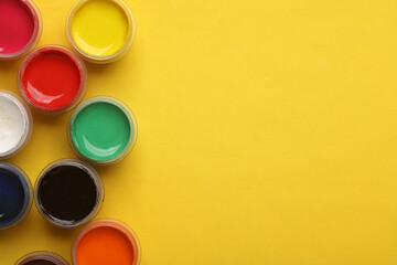 Jars of gouache paint on a yellow background. Copy space