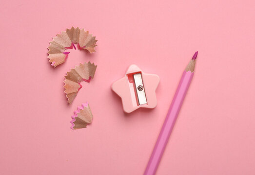 Sharpened pencil with shavings and sharpener on pink background