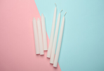 White wax candles on pink blue pastel background