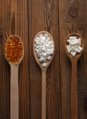 Various pills in wooden spoons. Medicine concept