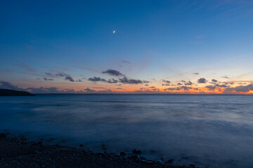 Pose longue au coucher de soleil, capturant la majesté de la mer d'Iroise depuis une plage de la...