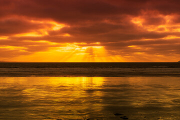 Le soleil décline sur une plage de la Presqu'île de Crozon en Bretagne, peignant le ciel et la...