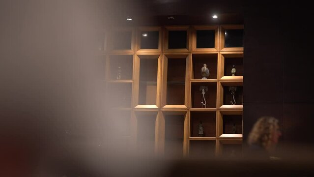 Agadir, Morocco - February 25, 2024 - A wooden shelving unit displays various figurines, partially obscured by a blurred foreground.