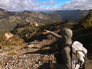 A man points to a distant mountain while backpacking in the Cascades of Washington State.