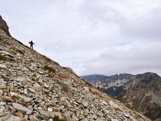 A man descends a steep, rocky slope while hiking in the mountains of Washington State. 