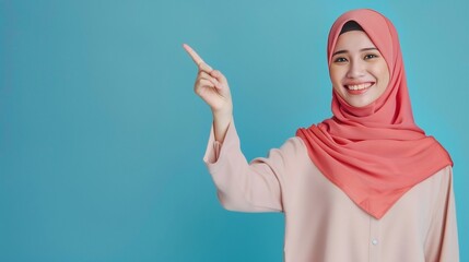 Portrait of beauty Asian girl wearing hijab smiling and pointing her hand to left, Studio shot, modern clothing, pastel color, copy space for text and products 