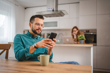 man with eyeglasses stand at home use mobile phone sms texting