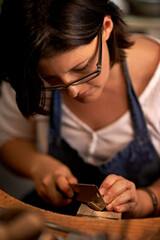 Carving, wood and artist in workshop with tools for creative project or sculpture on table at night. Artisan, carpenter and woman with talent for creativity in dark studio in process of woodworking