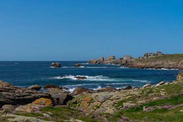 Côte rocheuse bretonne sous un ciel bleu printanier, décorée de lichen sur les rochers et...
