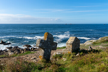 Surplombant l'horizon maritime en Bretagne, une croix ancestrale se tient aux côtés d'une fontaine, symboles de foi et de purification, évoquant l'âme profonde et la tradition de cette région côtière.