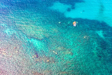aerial view waves crashing on the rock beside the beach..white bubble waves in turquoise sea on the rock. .creative nature and travel concept.