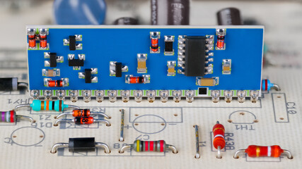 Integrated circuit and surface mounted electronic components on a blue PCB. Close-up a hybrid module in white printed wiring board with through-hole technology in part of gas burner automatic control.
