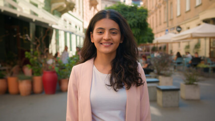 Close up portrait smiling calm young Indian Arabian ethnic woman female girl student businesswoman standing city street cafe outside slowly opening eyes friendly wide toothy healthy smile dental care