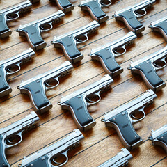 Sleek Silver Semi-Automatic Pistols Arranged on Textured Wooden Table