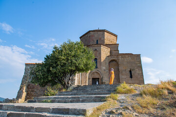 one girl in an orange dress and a white scarf stands near the old church