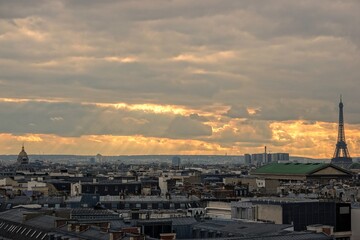 Vue panoramique sur le ciel de Paris en hauteur et rayons du soleil traversant les nuages, avec effet d'accentuation de lumière chaude