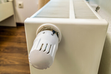 A white radiator with a white knob on it. The knob is turned to the left. The radiator is on a...