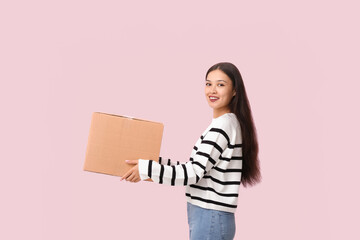 Pretty young woman with parcel on pink background