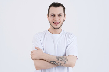 Portrait of attractive caucasian young man with tattoos in casual clothes with crossed arms...
