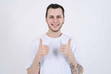 Attractive caucasian young man with tattoos in casual clothes showing thumbs up isolated on white studio background. Excellent, Agree, Approval