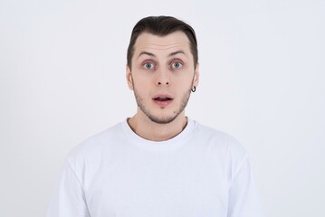 Portrait of shocked attractive caucasian young man in casual clothes with open mouth isolated on white studio background