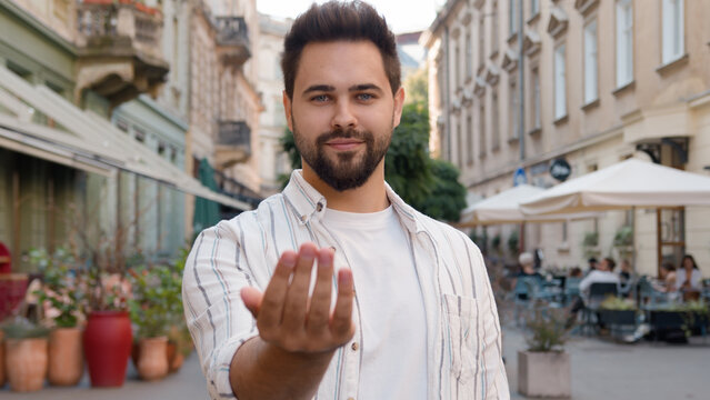 Successful handsome Caucasian European man young confident guy businessman beckon symbol sign smiling street city outside invite welcome cheerful friendly male greeting gesturing join coming call up