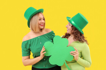 Happy women with paper clover on yellow background. St. Patrick's Day